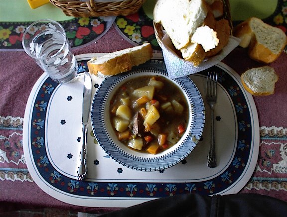 A bowl of soup and bread on a plate

Description automatically generated