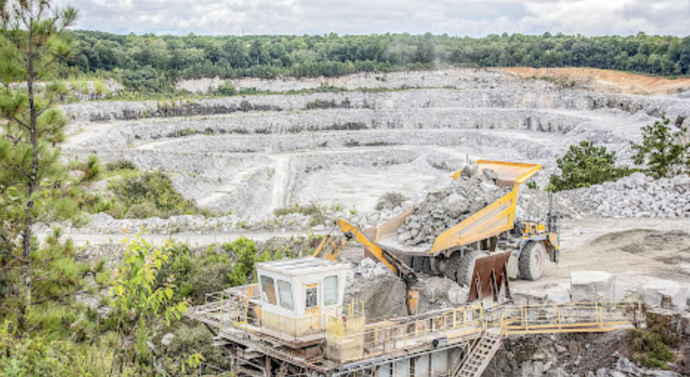 A construction vehicle loading rocks into a quarry

Description automatically generated