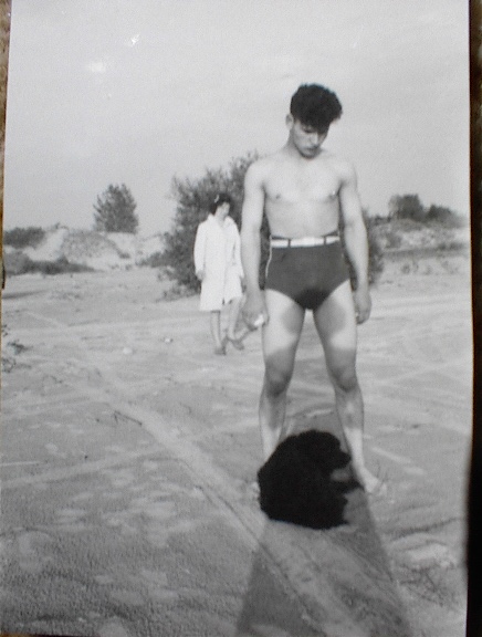 A person in swimsuit with a dog

Description automatically generated